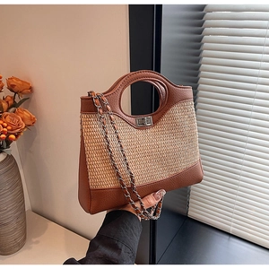 Détail du sac seau bicolore tenu à la main avec texture tissée et garniture en cuir