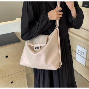 Détail d'un sac cabas matelassé beige avec fermoir rotatif argenté et texture en cuir