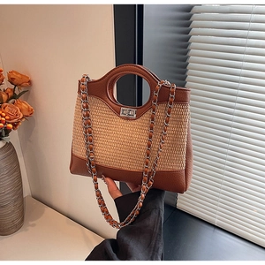 Détail du sac seau en paille tressée avec bordure en cuir marron, fermoir et chaîne