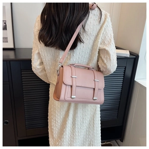 Detail of pink leather crossbody bag with lychee texture and metallic buckle straps