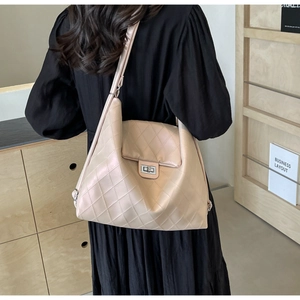 Vue arrière du modèle portant un sac cabas beige matelassé avec fermoir rotatif argenté