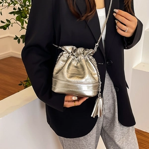 Sac seau argenté avec texture crocodile et cordon, porté par un mannequin chic