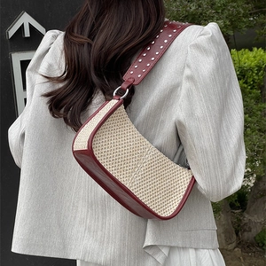 Straw hobo bag with red leather trim and silver studded wide strap on female model