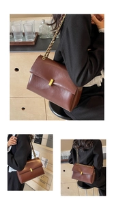 Detail view of dark coffee leather handbag featuring gold chain strap and metal clasp closure