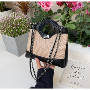 Détail d'un sac seau en paille tressée avec garniture en cuir noir et fermoir en métal argenté