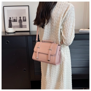 Detail of light pink leather crossbody bag with silver buckles worn by a model