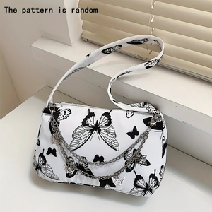 Detail of canvas underarm bag featuring black butterfly prints and silver metal chains