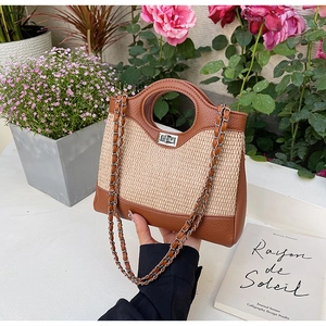 Détail d'un sac seau tissé avec patchwork en cuir et poignée circulaire évidée