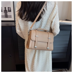 Close-up of beige lychee grain leather crossbody bag with silver buckles on model