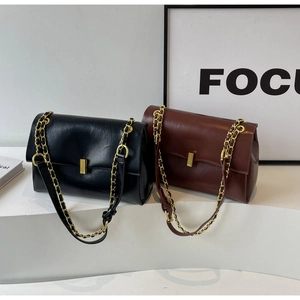 Detail showing high-quality leather texture and golden metal locks on black and brown handbags