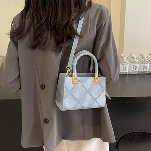 Chic light blue crossbody bag with denim texture, woven handles and golden hardware