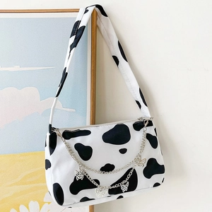 Detailed shot of cow print canvas bag featuring silver chains and butterfly charms
