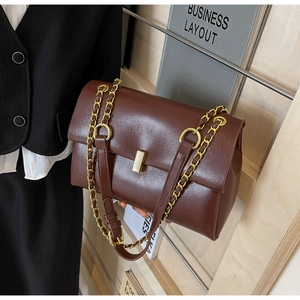 Detailed view of brown oil wax leather handbag with gold square lock and chain strap