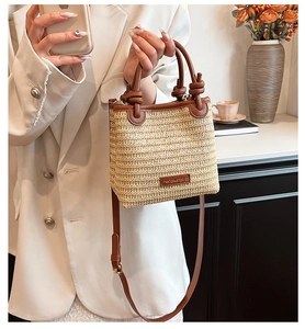 Detail of woven straw shoulder bag with leather trim and branded metal plaque