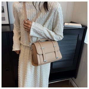 Detail of a chic apricot crossbody bag with lychee texture and silver metal buckles