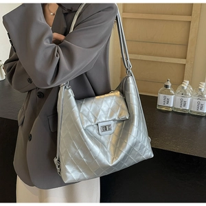 Détail du sac fourre-tout argenté matelassé avec fermoir rotatif et bandoulière chic