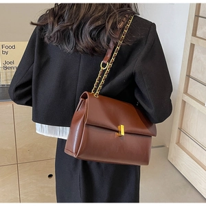 Detailed view of the dark brown chain strap tote bag on a model's shoulder