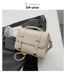 Detail of off-white leather Boston bag with double straps and metallic buckle detail