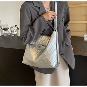 Gros plan d'un sac cabas argenté matelassé avec texture métallique et fermoir rotatif