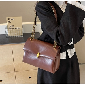 Detail of a dark brown vintage oil wax leather tote bag with golden chain and clasp