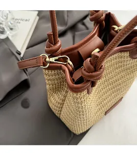 Detail of straw tote bag showing brown leather trim and detachable gold metal rings