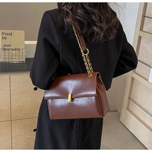 Detailed view of the dark brown leather shoulder bag featuring a gold chain strap