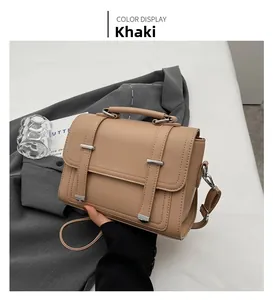 Detail of khaki pebbled leather handbag with silver metallic bars and top handle