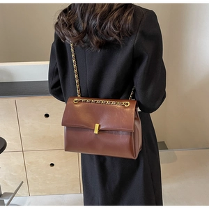 Rear view of brown leather chain tote bag on shoulder showing medium size and texture