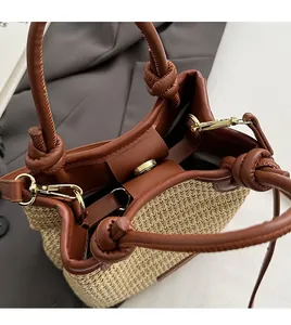 Detail of golden magnetic buckle and leather trim on a woven straw bucket bag