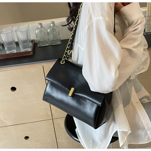 Close-up of black leather texture and gold metal buckle on chain shoulder bag