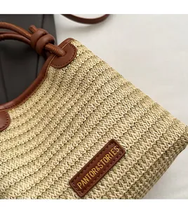 Close-up of woven straw texture with brown leather logo patch and handle details