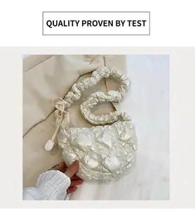 Detail of quilted cloud bag featuring pleated handle and silky texture in a warm setting