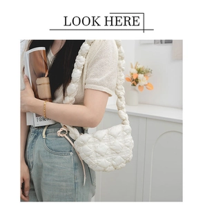 Detail of quilted puffy crossbody bag featuring soft crescent shape and wide padded strap