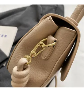 Gros plan sur cuir beige grainé avec boucle dorée et lanière à nœud décoratif