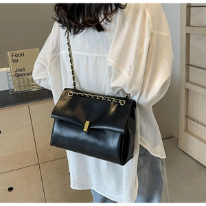 Close-up of black PU leather tote with gold chain strap and metal swivel lock detail
