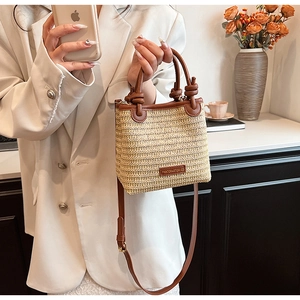 Detail of straw woven tote with brown leather trim and knotted handle design