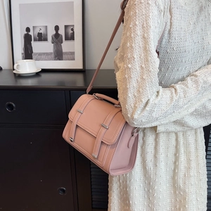 Pink minimalist crossbody flap bag with textured leather and silver buckles shown on model