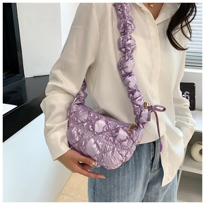 Detail of purple quilted puff bag showing glossy texture and ruffled shoulder strap