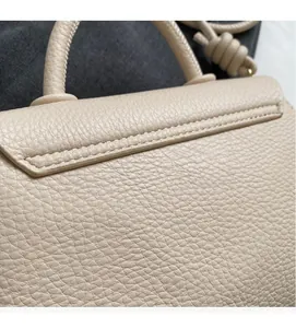Détail du cuir grainé et de la poignée nouée sur un sac besace de couleur beige