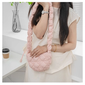 Detail view of pink quilted puffer bag with thick padded strap and soft texture