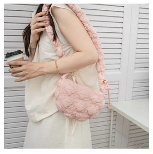 Close-up of pink quilted puffer bag showing crescent shape and padded fabric texture