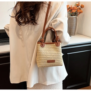 Close-up of woven straw bucket bag with leather handles and Pantora Stories logo tag