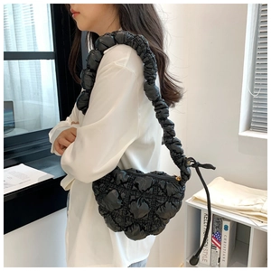Detail of a black quilted bubble cloud bag featuring a glossy finish and pleated strap