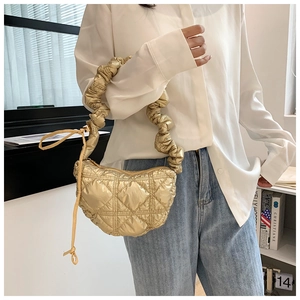 Detail of the glossy gold quilted texture and ruched handle on the crescent hobo bag