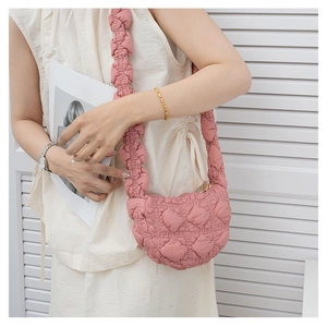 Close-up of pink quilted puffer bag with pleated shoulder strap and glossy texture