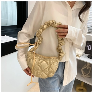 Detail of champagne gold quilted bag featuring pleated handle and metallic shine finish