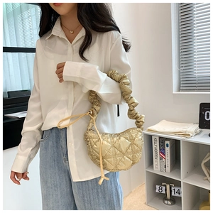 Detailed close-up of a golden quilted crescent hobo bag with unique ruched handle texture