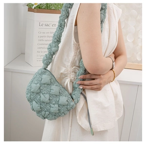 Close-up of light green quilted cloud bag with puffy texture and pleated strap detail