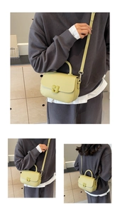 Détail du sac selle en cuir vert avocat avec boucle en J et texture grain de litchi