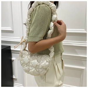Detailed close-up of white quilted puffer cloud bag with pleated strap on a shoulder